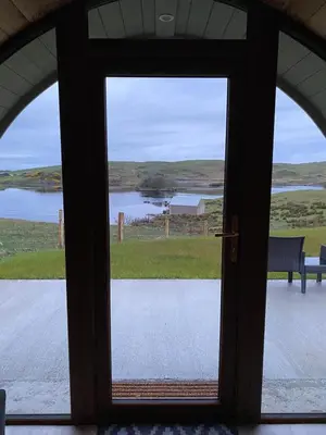 a door to a porch with a view of a lake at Fairhead Glamping Pods in Ballycastle