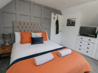 a bedroom with an orange and white bed with a television at Ben View in Arrochar