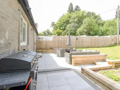 a backyard with a grill and a couch and a table at Ben View in Arrochar