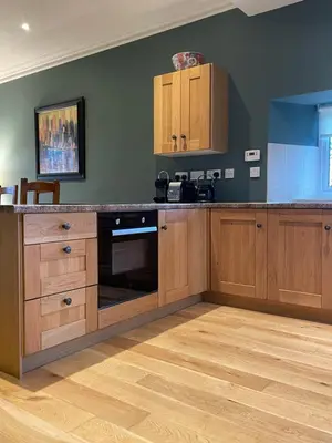 a kitchen with wooden cabinets and a counter top at Luxury Garden Cottage in Dalry
