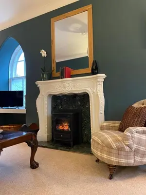 a living room with a fireplace and a mirror at Luxury Garden Cottage in Dalry