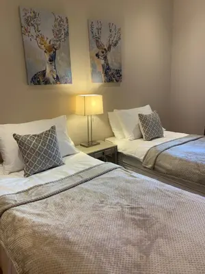two beds in a bedroom with paintings on the wall at Lomond View in Luss