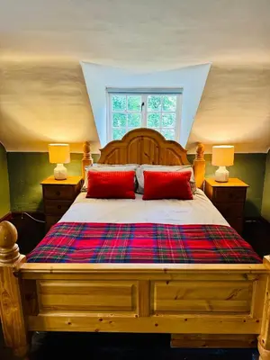 a bedroom with a wooden bed with two red pillows at East Cottage at Powis House Estate in Stirling