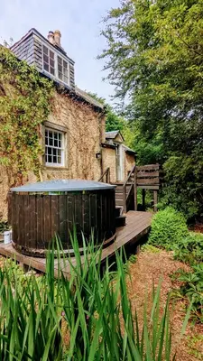 a wooden ramp leading to a building with a hot tub at East Cottage at Powis House Estate in Stirling