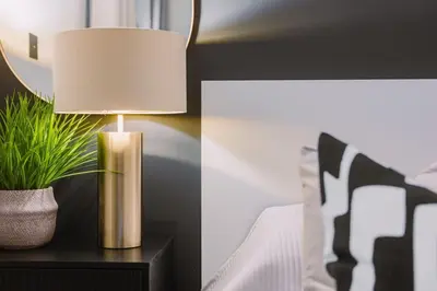 a lamp on a nightstand next to a bed at ComfySleep ApartHOUSE in Glasgow