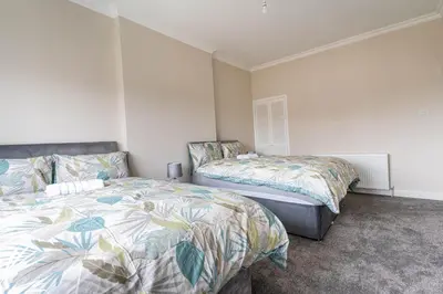 a bedroom with two beds in a room at 4 Bedrooms Homely House - Sleeps 6 Comfortably with 6 Double Beds,Glasgow, Free Street Parking, Business Travellers, Contractors, & Holiday-Goers, Near All Major Transport Links in Glasgow & City Centre, Perfect for Common Wealth Games 2026 in Glasgow