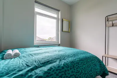 a bedroom with a bed with two towels on it at 4 Bedrooms Homely House - Sleeps 6 Comfortably with 6 Double Beds,Glasgow, Free Street Parking, Business Travellers, Contractors, & Holiday-Goers, Near All Major Transport Links in Glasgow & City Centre, Perfect for Common Wealth Games 2026 in Glasgow