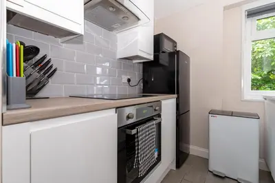 a kitchen with white cabinets and a stove top oven at 4 Bedrooms Homely House - Sleeps 6 Comfortably with 6 Double Beds,Glasgow, Free Street Parking, Business Travellers, Contractors, & Holiday-Goers, Near All Major Transport Links in Glasgow & City Centre, Perfect for Common Wealth Games 2026 in Glasgow