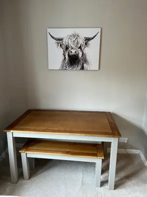 a wooden table with a picture of a cow on a wall at Cosy Cottage Apartment in Helensburgh