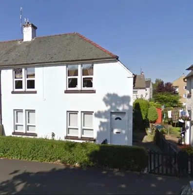 a white house with a driveway in front of it at Cosy Cottage Apartment in Helensburgh