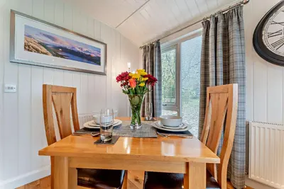 a dining room table with a vase of flowers on it at Lomond View in Langbank