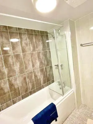 a bathroom with a shower and a tub and a sink at 3 bed house with parking near airport in Edinburgh