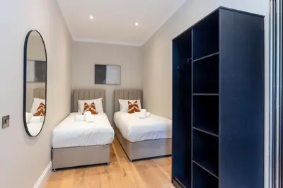 a bedroom with two beds and a mirror at Dragon Suites Luxury Serviced Apartments at Walker Street in Edinburgh